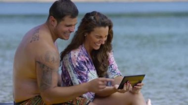 Çift dijital tablet kullanarak gölün kenarında oturuyor