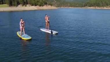 Göl kenarında kürek çeken çiftlerin havadan drone görüntüleri.