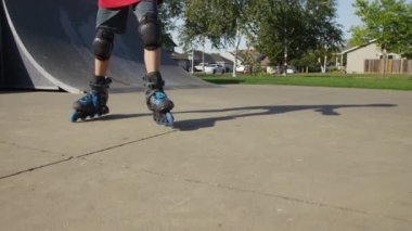 Çocuk parkta paten kayıyor, ayaklara yakın.