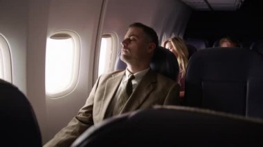 Uçaktaki adam pencereyi kapatır ve dinlenir.