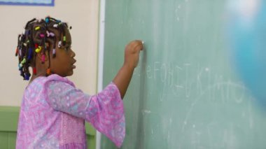 Okulda tahtaya yazı yazan öğrenci.