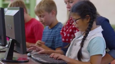 Öğretmen ve öğrenci okulda bilgisayar üzerinde çalışıyor.