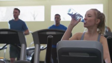 Spor salonunda su içen bir kadın