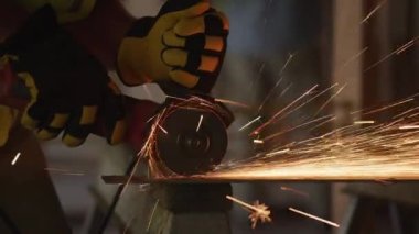 İnşaat işçisi metali öğütüyor ve kıvılcımlar saçıyor.