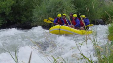 Bir grup insan ağır çekimde rafting yapıyor.