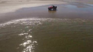 Sahilde giden 4x4 off road aracının hava görüntüsü.