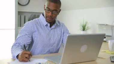 İşadamı ofiste bilgisayarla çalışıyor.