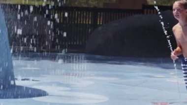 Çocuk yaz günü çeşmeden atlıyor, ağır çekimde.