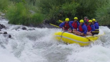 Bir grup insan ağır çekimde rafting yapıyor.