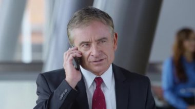 Olgun iş adamı ofis lobisinde cep telefonu kullanıyor.