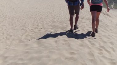 Kum tepelerinde yürüyüş yapan bir çift.