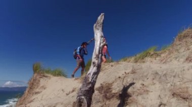 Kumsalda kum tepelerinde yürüyüş yapan bir çift.