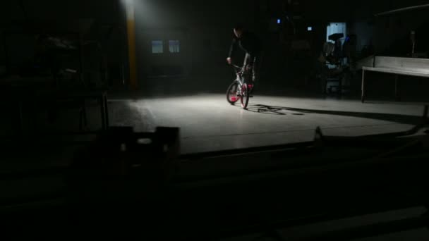 Bmx 骑手在黑暗的仓库中玩把戏 — 图库视频影像