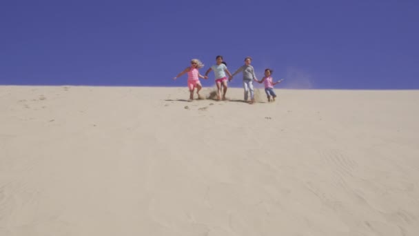 ビーチで砂丘を走っている子供たちのグループ — ストック動画