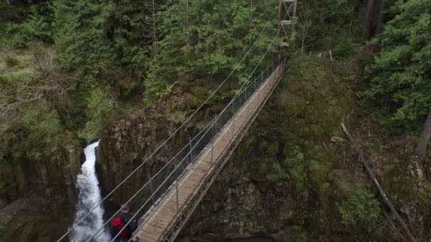 Backpacker Cruza Puente Colgante Sobre Cascada — Vídeos de Stock