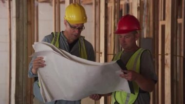 İnşaat işçileri planlara bakıyor.