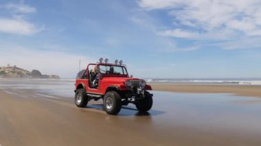 4x4 plajda araba kullanan bir çift.