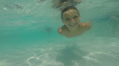 Su altında havuzda yüzen genç bir çocuk, POV videosu.