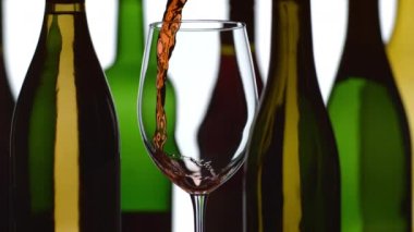 Kırmızı şarap arka planda şişelerle ağır çekimde akıyor; Fantom Flex 4K 'de 1000 fps hızla çekiliyor