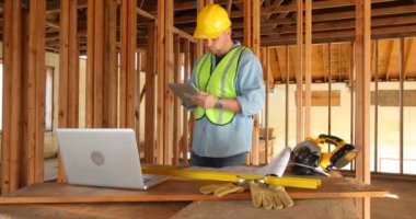 Dijital tablet ve dizüstü bilgisayar kullanan inşaat işçisi