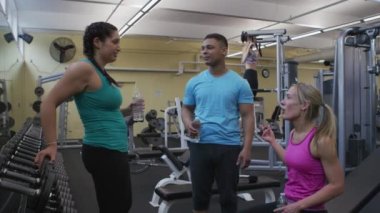 Spor salonunda birlikte konuşan bir grup insan.