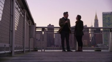 New York City 'de arka planda şehir silüeti olan bir çift iskelede duruyor.