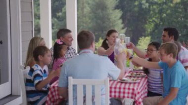 Bir grup insan arka bahçede barbekü yiyor ve eğleniyor.