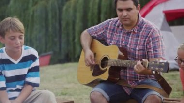 Yaz kampındaki çocuklar kamp ateşinde lokum kızartıyorlar.