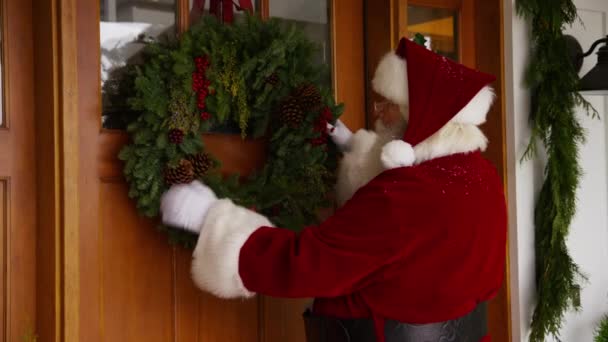 Papai Noel Colocando Grinalda Porta — Vídeo de Stock