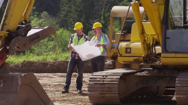 Δύο Εργάτες Από Εξοπλισμό Ανασκαφών Εξετάζουν Σχέδια — Αρχείο Βίντεο