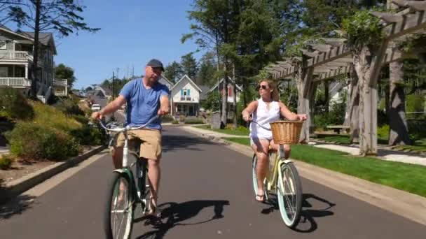 Ζευγάρι Ποδήλατο Ιππασίας Μαζί Στην Παραθαλάσσια Κοινότητα Διακοπών — Αρχείο Βίντεο