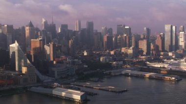 New York City 2017 dolaylarında, Manhattan binaları ve rıhtımlarıyla gündoğumunda Hudson Nehri 'nde uçuyor. Cineflex ve RED Epic-W Helyum ile çekilmiştir..