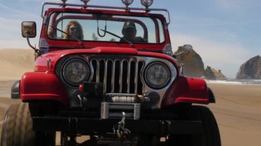 4x4 plajda araba kullanan bir çift.