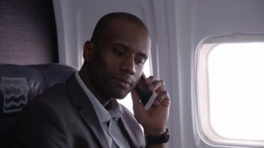 İş adamı uçak uçuşunda cep telefonuyla konuşuyor.