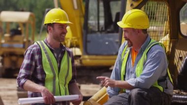 İki işçi birlikte iş sitede konuşuyor