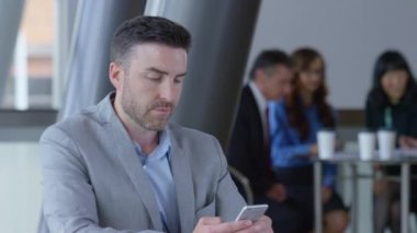 Genç işadamı ofis lobisinde cep telefonu kullanıyor.