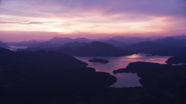 İngiliz Kolombiyası 2018 dolaylarında. Gün batımında göl ve tepelerin havadan görünüşü. Helikopterden Cineflex gimbal ve RED Epic-W kamerasıyla çekildi..