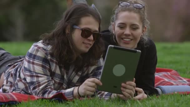 Dois Jovens Parque Cobertor Olhando Para Tablet Digital Juntos — Vídeo de Stock