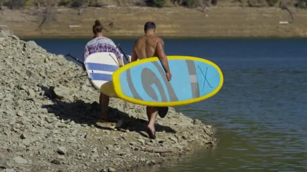 Paar Wandelen Bij Het Meer Met Stand Paddle Boards — Stockvideo