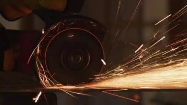 İnşaat işçisi metali öğütüyor ve kıvılcımlar saçıyor.