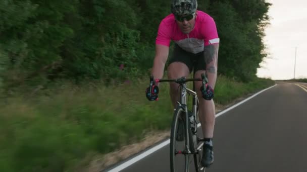 田舎道で男のサイクリストの追跡ショット 商用利用のために完全リリース — ストック動画