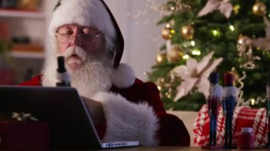 Noel Baba atölyede dizüstü bilgisayar kullanıyor.