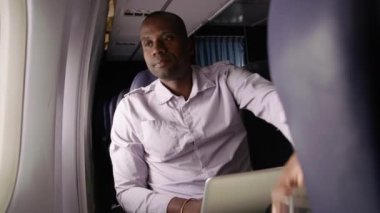 Uçakta dizüstü bilgisayarda çalışan adam.