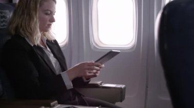 Uçakta dijital tablet kullanan genç iş kadını