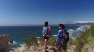 Kumsalda kum tepelerinde yürüyüş yapan bir çift.