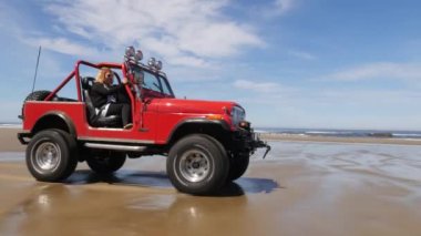4x4 plajda araba kullanan bir çift.