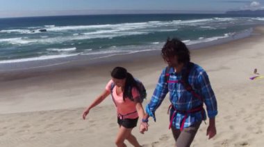 Kumsalda kum tepelerinde yürüyüş yapan bir çift.