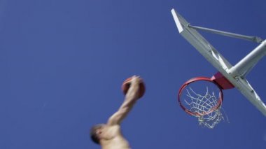 Düşük açılı yavaş çekim yapan bir adam basketbol turnikesi yapıyor.