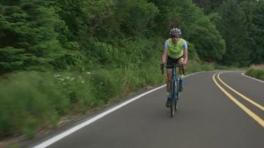 Country Road 'da bir kadın bisikletçinin görüntüsü. Ticari kullanım için tamamen serbest.