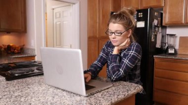 Evde dizüstü bilgisayarda çalışan genç bir kadın.